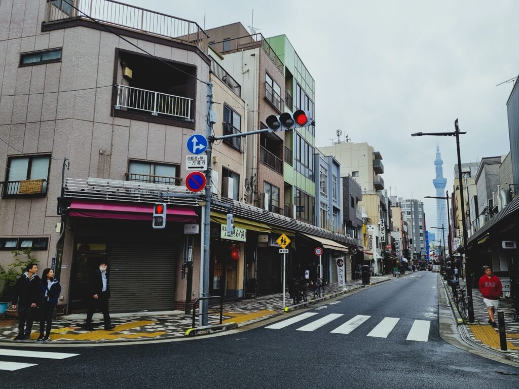 Street scene in Tokyo with pedestrians and the iconic Tokyo Skytree visible in the distance.